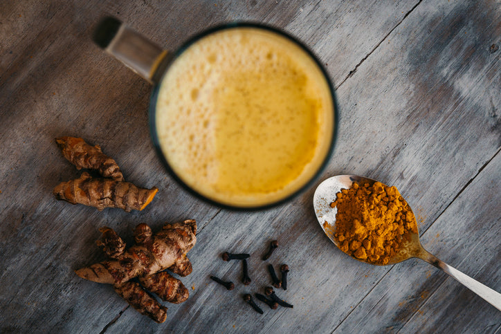 Turmeric latte drink close-up top view. Turmeric root and powder.